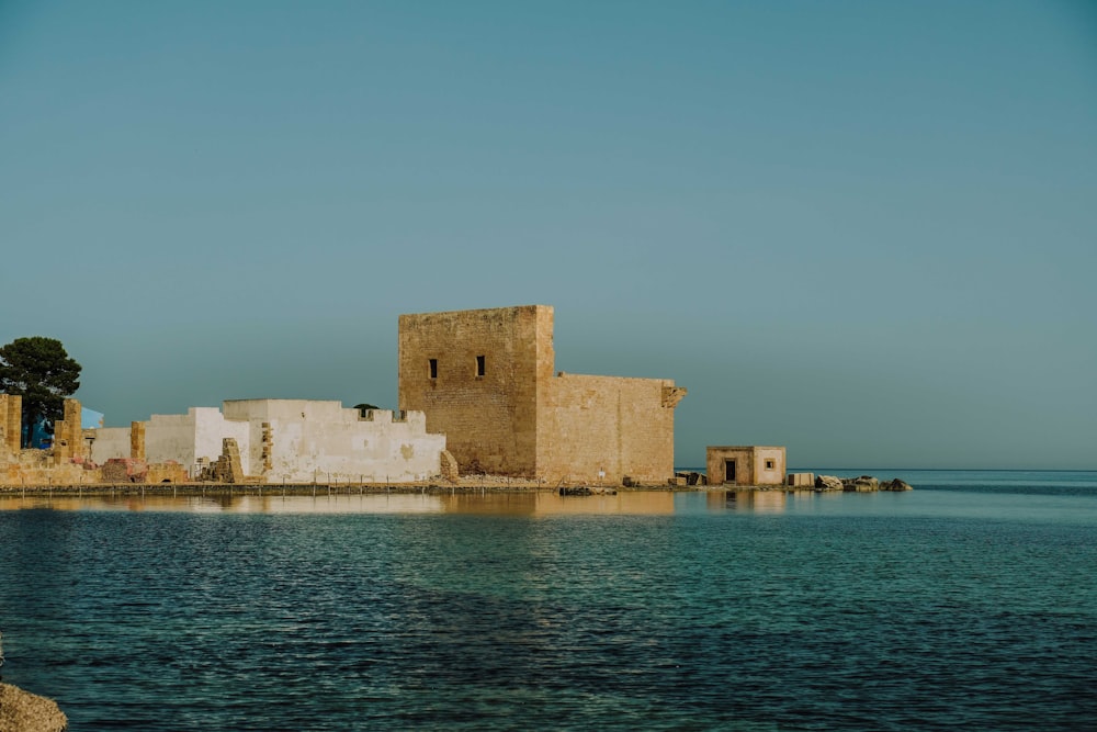 a stone building on a hill by the water