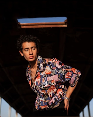 A close-up of a person wearing a bold Jam Ras geometric tee under warm sunlight.