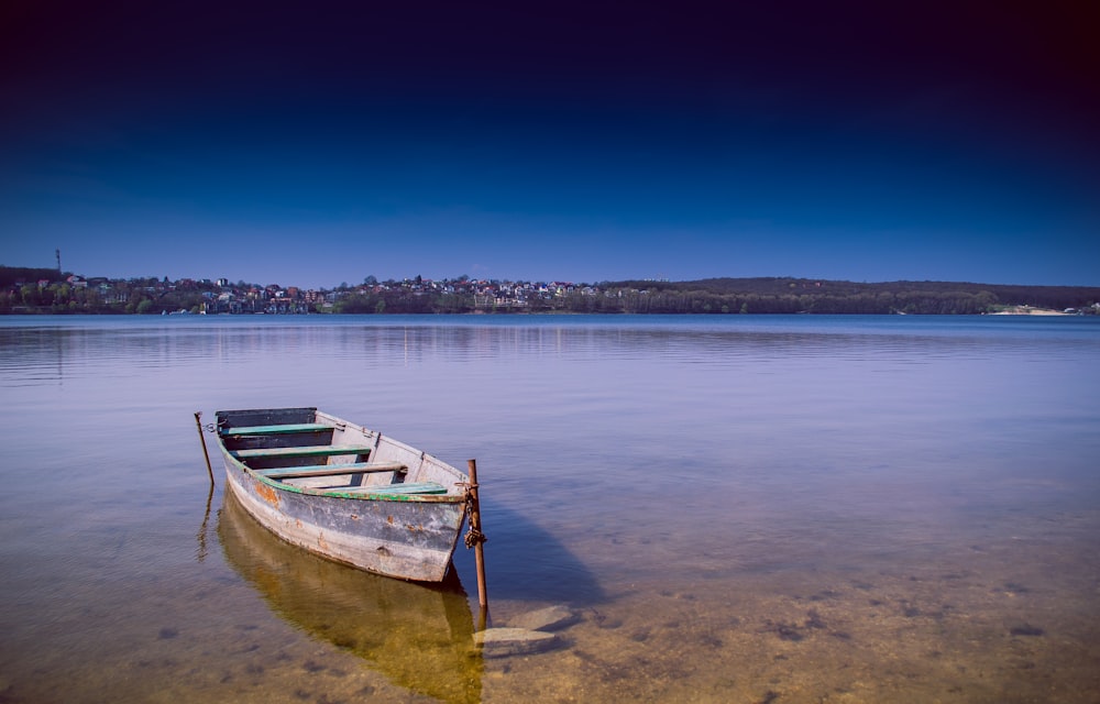 a boat sits on the shore of a lake