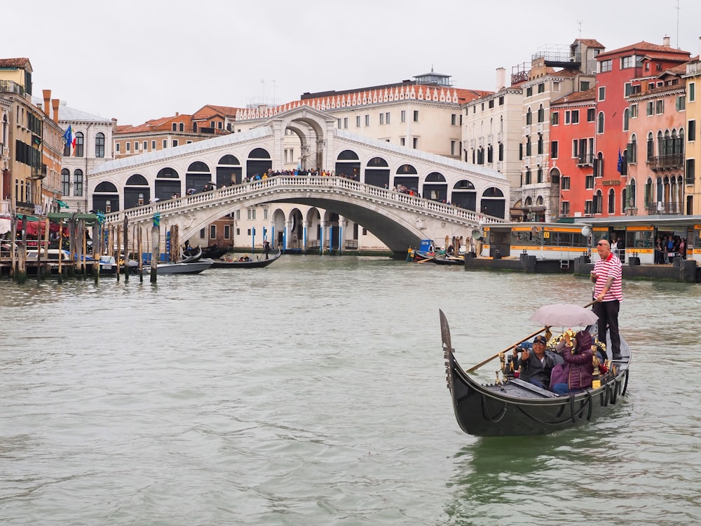 a boat travels through a canal with Rialto Bridge in the background