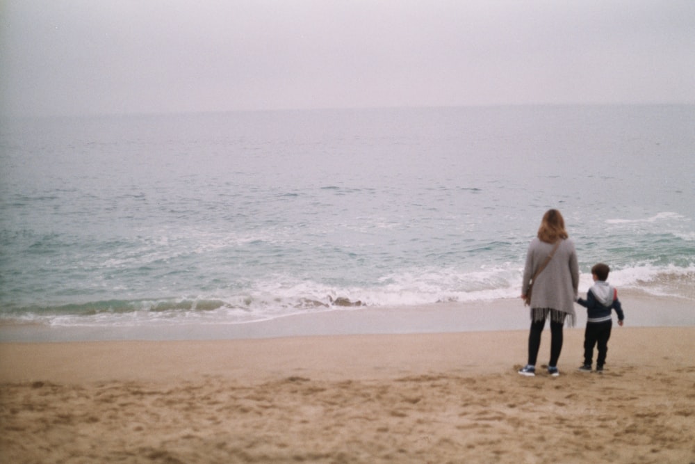 a person and a child walking on a beach