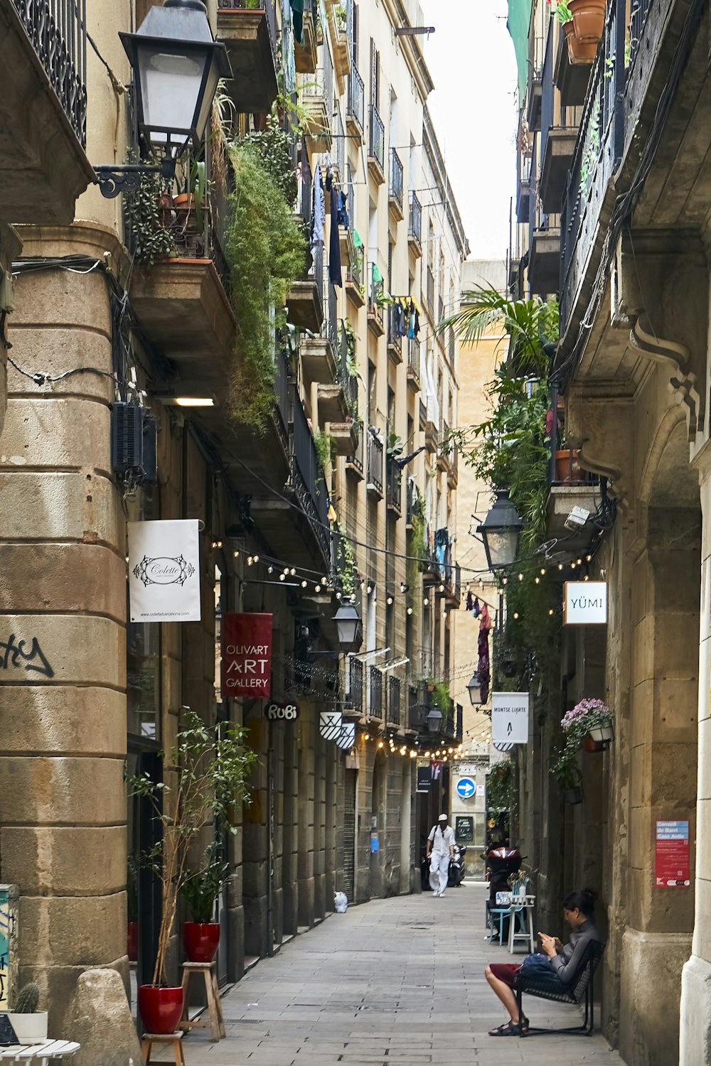 a person sitting on a bench in a narrow alley between buildings