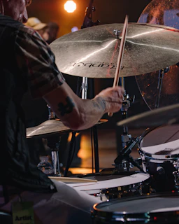 The drummer caught in motion, sticks flying as the beat drives the energy of the night