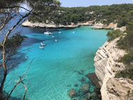 A secluded ocean cove with crystal-clear turquoise waters and a private yacht anchored.