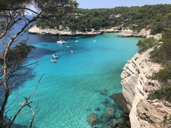 A cozy boat anchored near a hidden cove in Mallorca with crystal-clear turquoise waters.