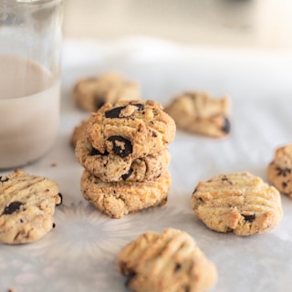 Freshly baked chocolate chip cookies stacked beside a glass of milk on a cozy kitchen counter.