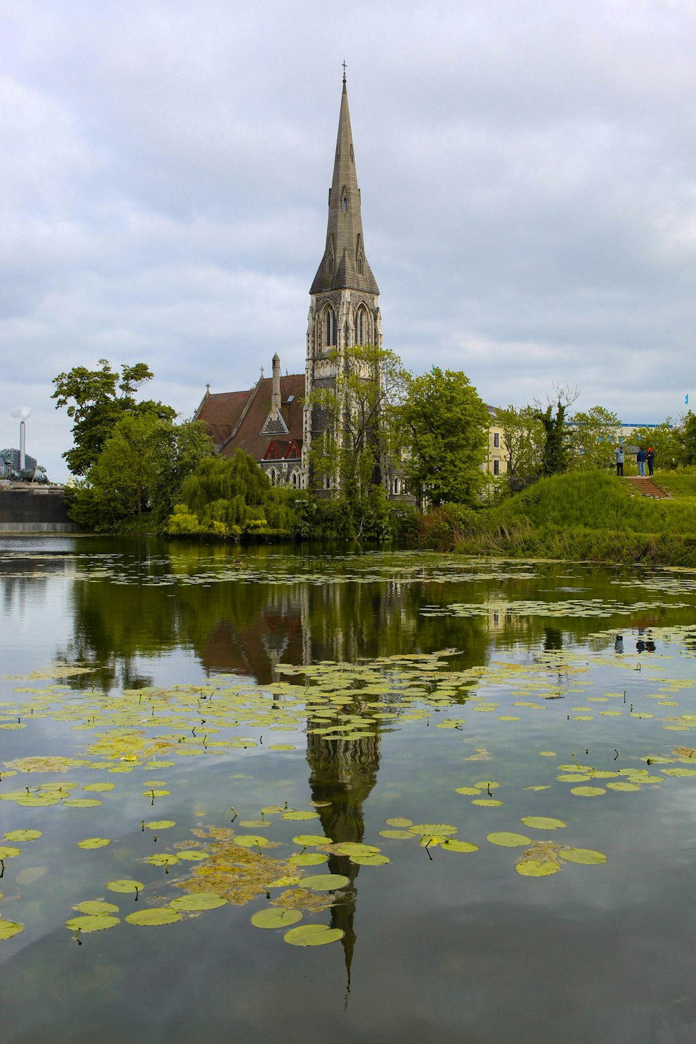 a building with a tower and trees by a body of water