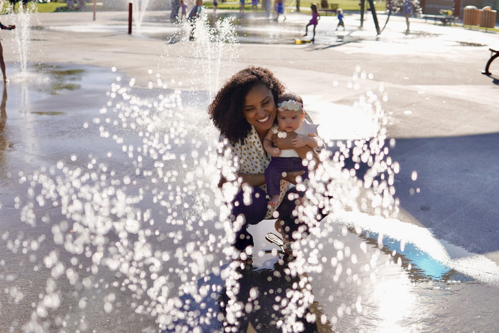 a person holding a baby in a fountain