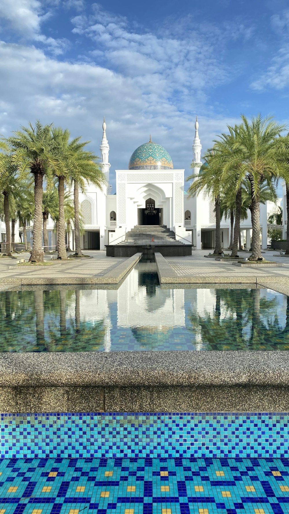 a white building with a dome and palm trees in front of it