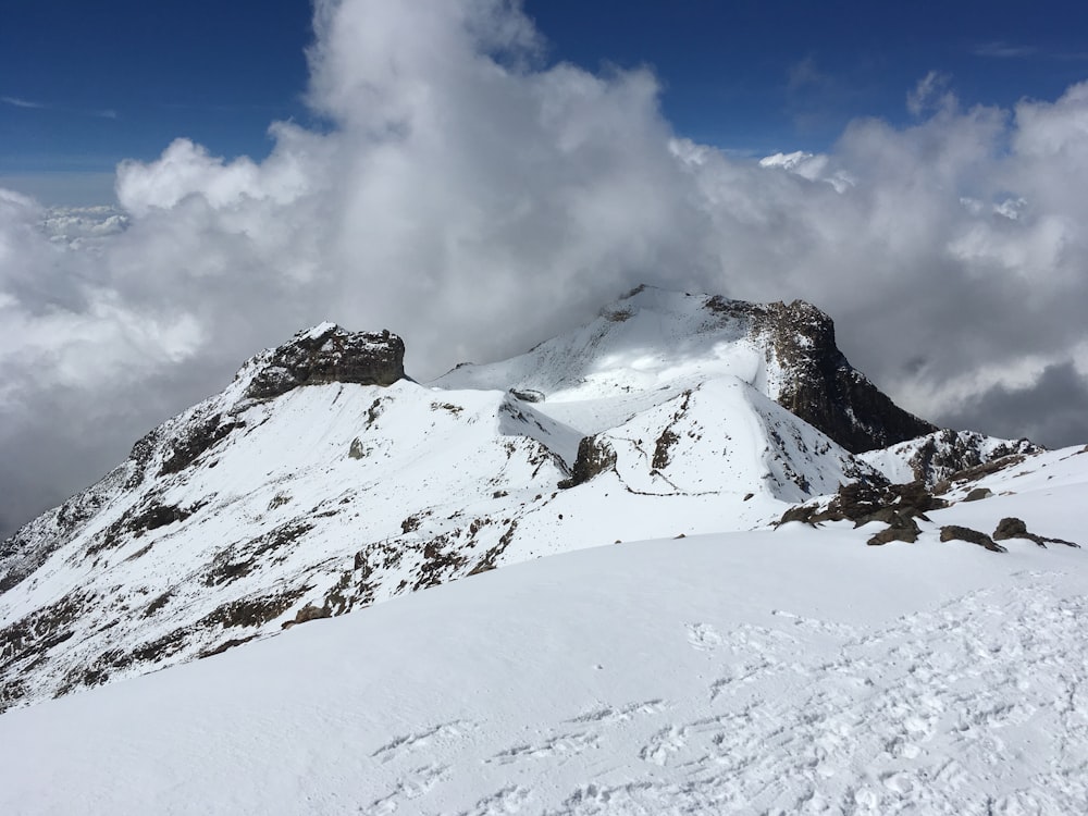 a snowy mountain with clouds