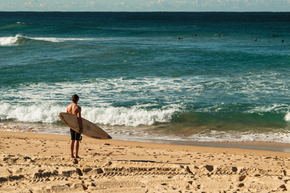 a man carrying a surfboard on a beach