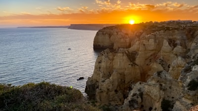 Sunset over the rugged cliffs of the Peruvian coast with a small boat in the distance.
