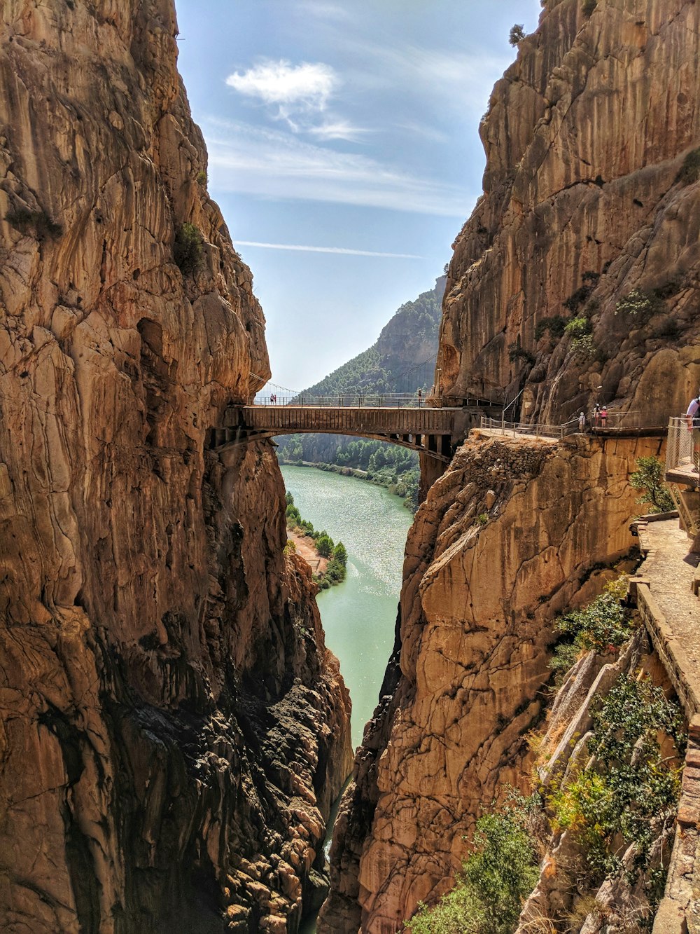a bridge over a river between cliffs