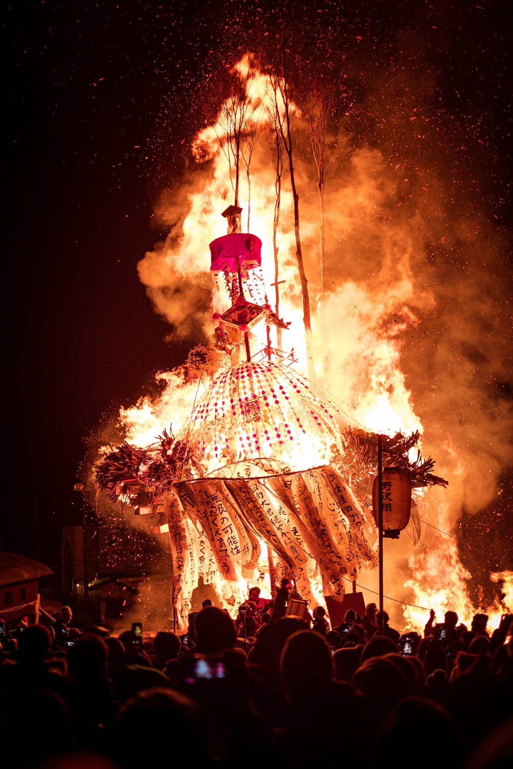a large group of people watching a person on a tower with fire