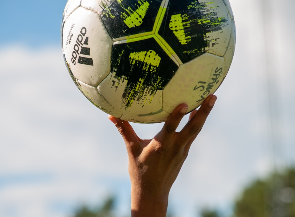 a hand holding a yellow and black ball