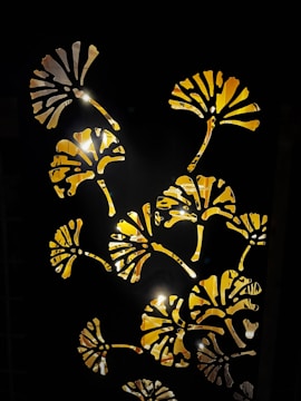 A decorative pattern featuring floral cutouts with light illuminating from behind. The floral designs are silhouetted against a dark background, creating a striking contrast.