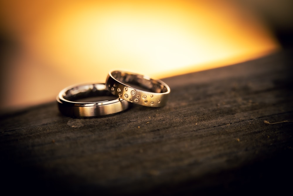 a pair of wedding rings on a wooden surface