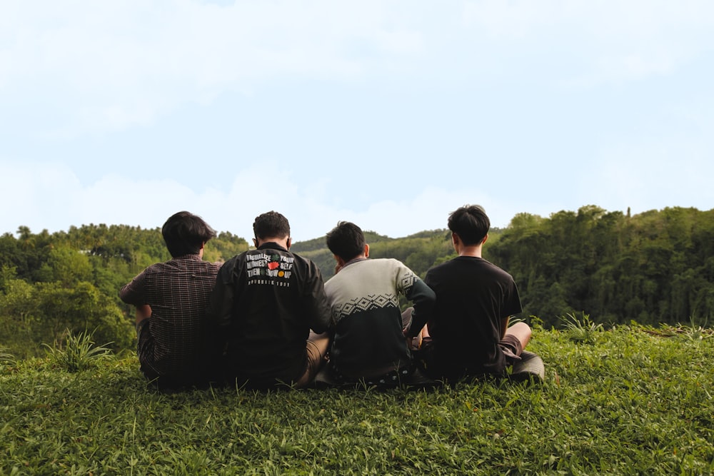 un groupe de personnes assises dans un champ herbeux regardant les arbres