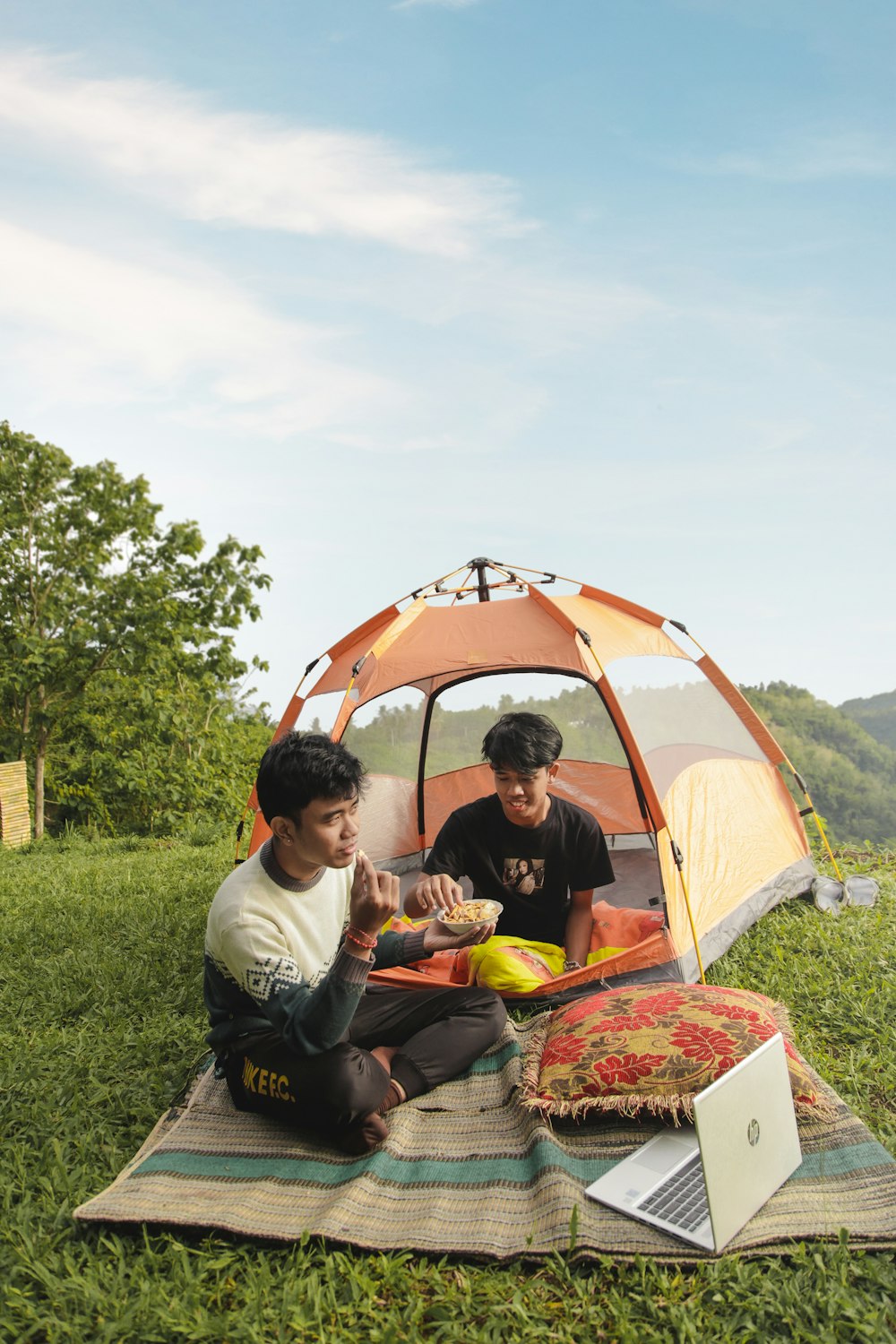 Un couple d’hommes assis dans une tente en train de manger de la nourriture