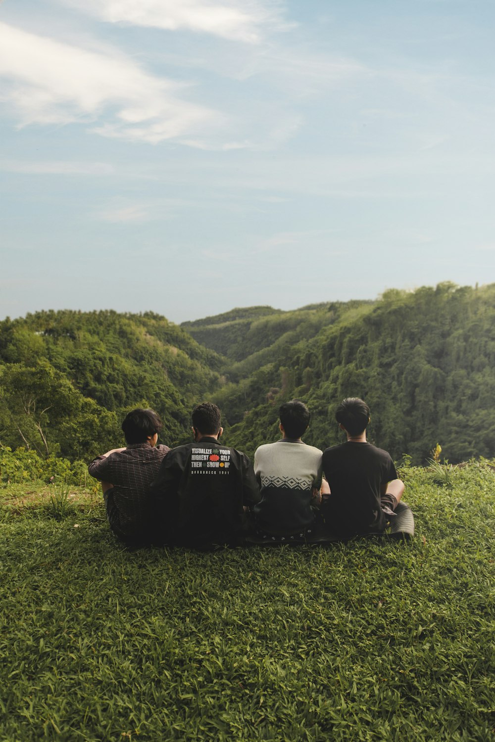 a group of people sitting in a grassy field looking at a hill