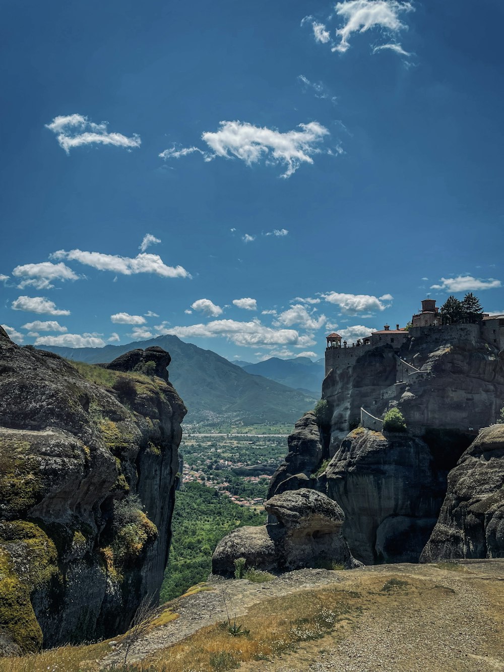 a rocky cliff with a city below