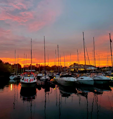 A vibrant marina scene at sunset with boats docked and people preparing for a sailing adventure.
