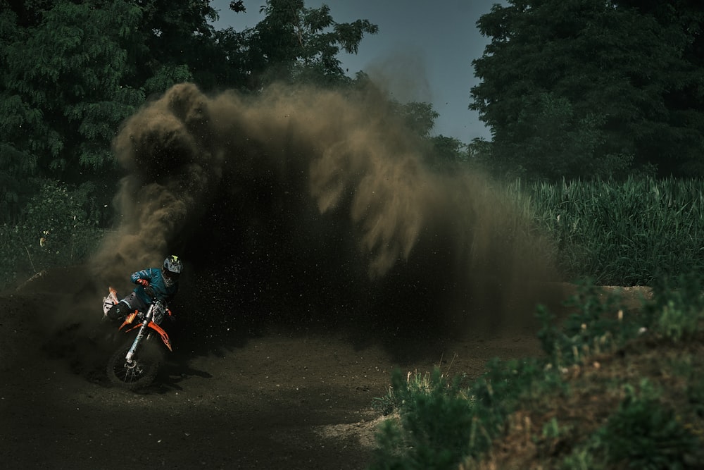 a person riding a motorcycle on a dirt road with a large explosion