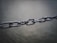A close-up of a metal chain with multiple links connected, captured in a shallow depth of field. The background is blurred, emphasizing the chain's detail and metallic texture.