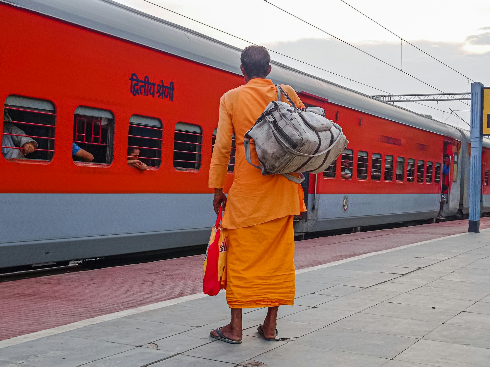 a man in an orange robe walks down a sidewalk