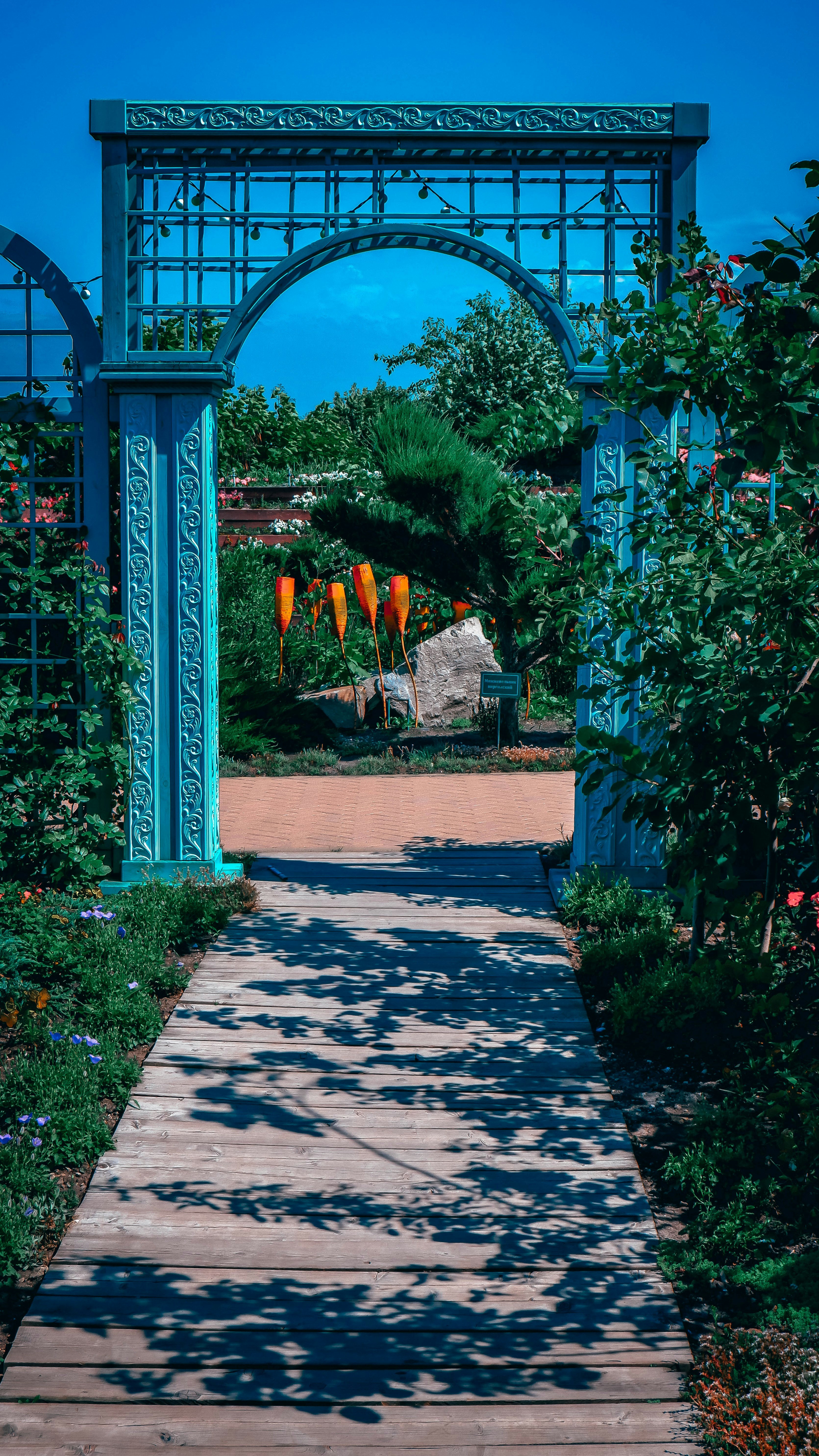 a walkway with plants and a sign
