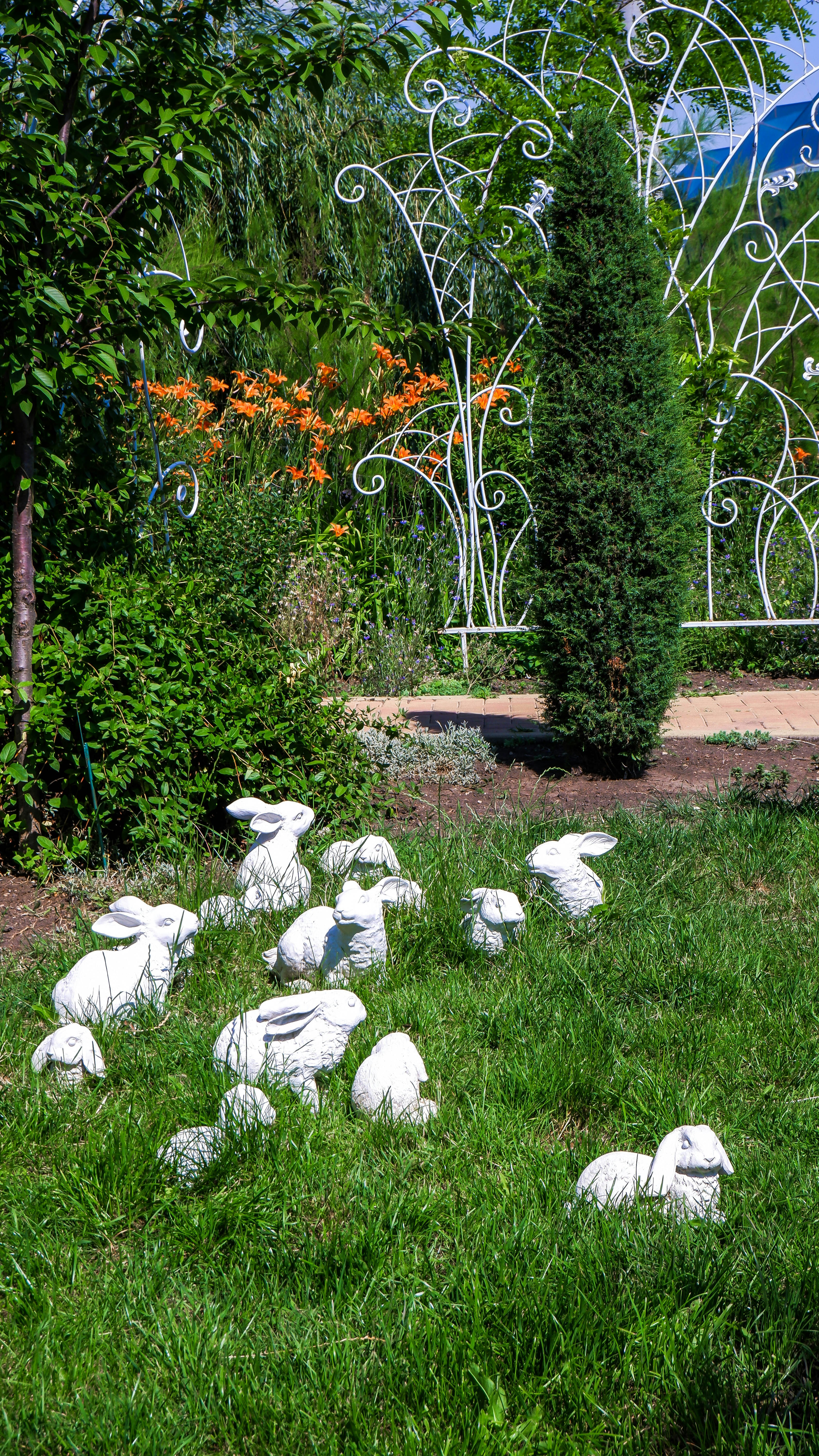 a group of white rabbits in a grassy area with trees and a ferris wheel in the background