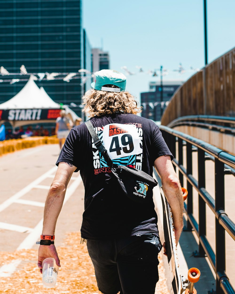 a man with a hat and a skateboard on a bridge