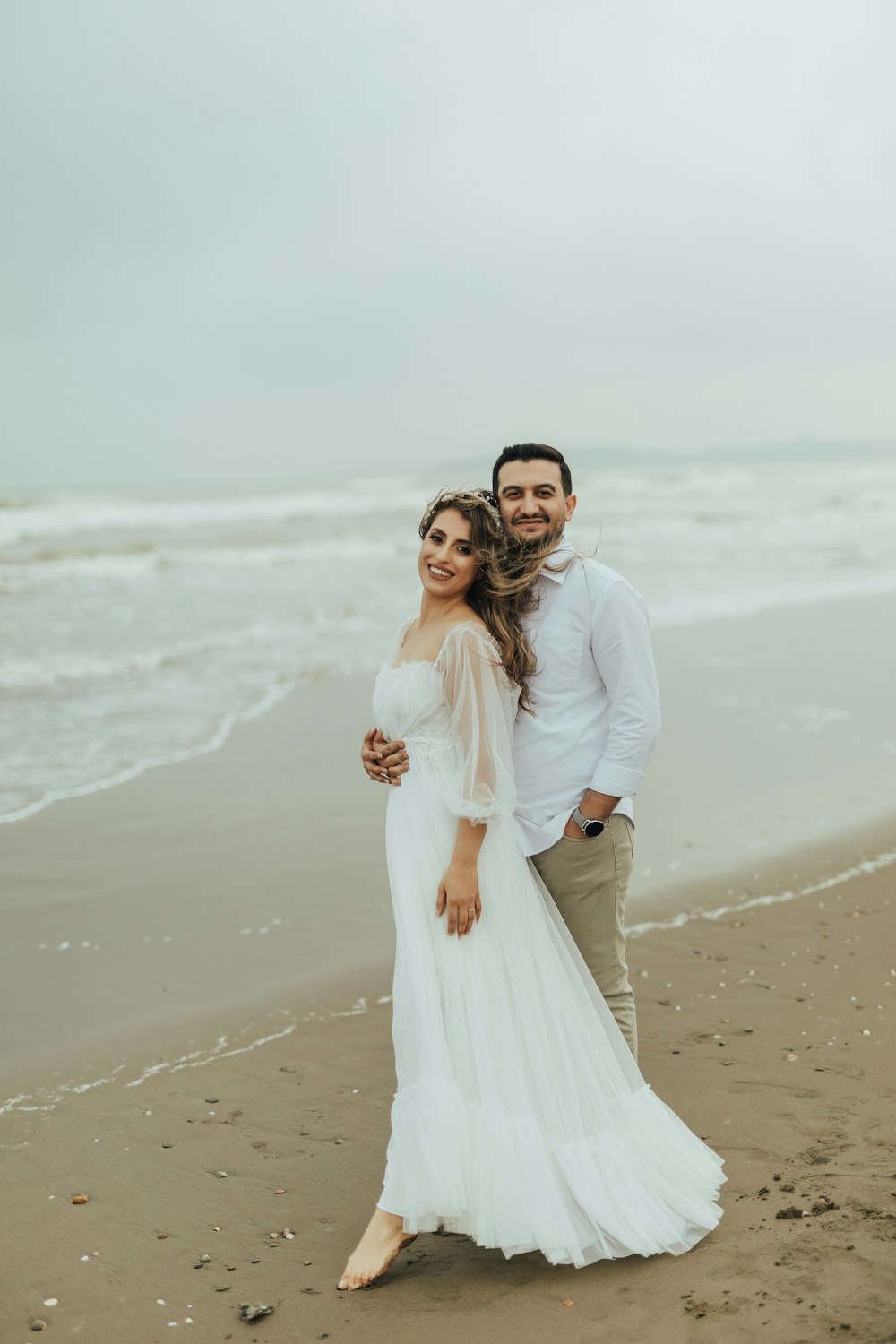 a man and woman posing on a beach