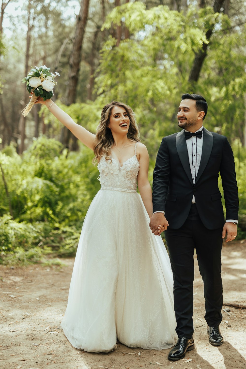 a man and woman walking down a path with flowers in their hands