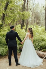 a man and woman walking down a path in a forest