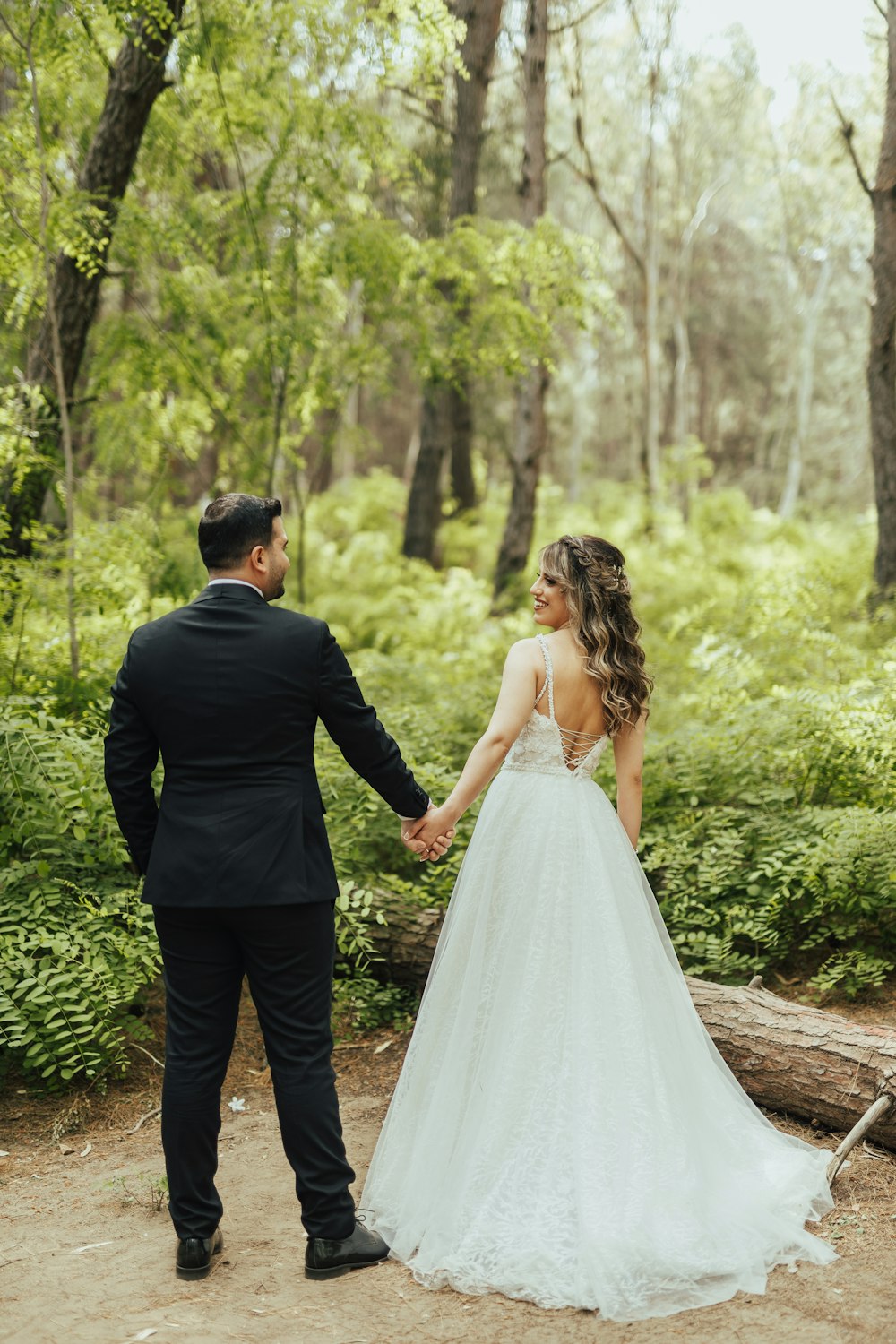 a man and woman walking down a path in a forest