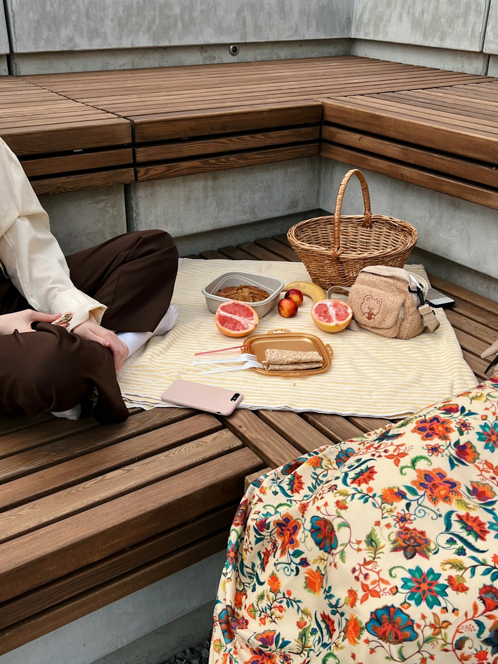 a person sitting on a bench with food and a basket