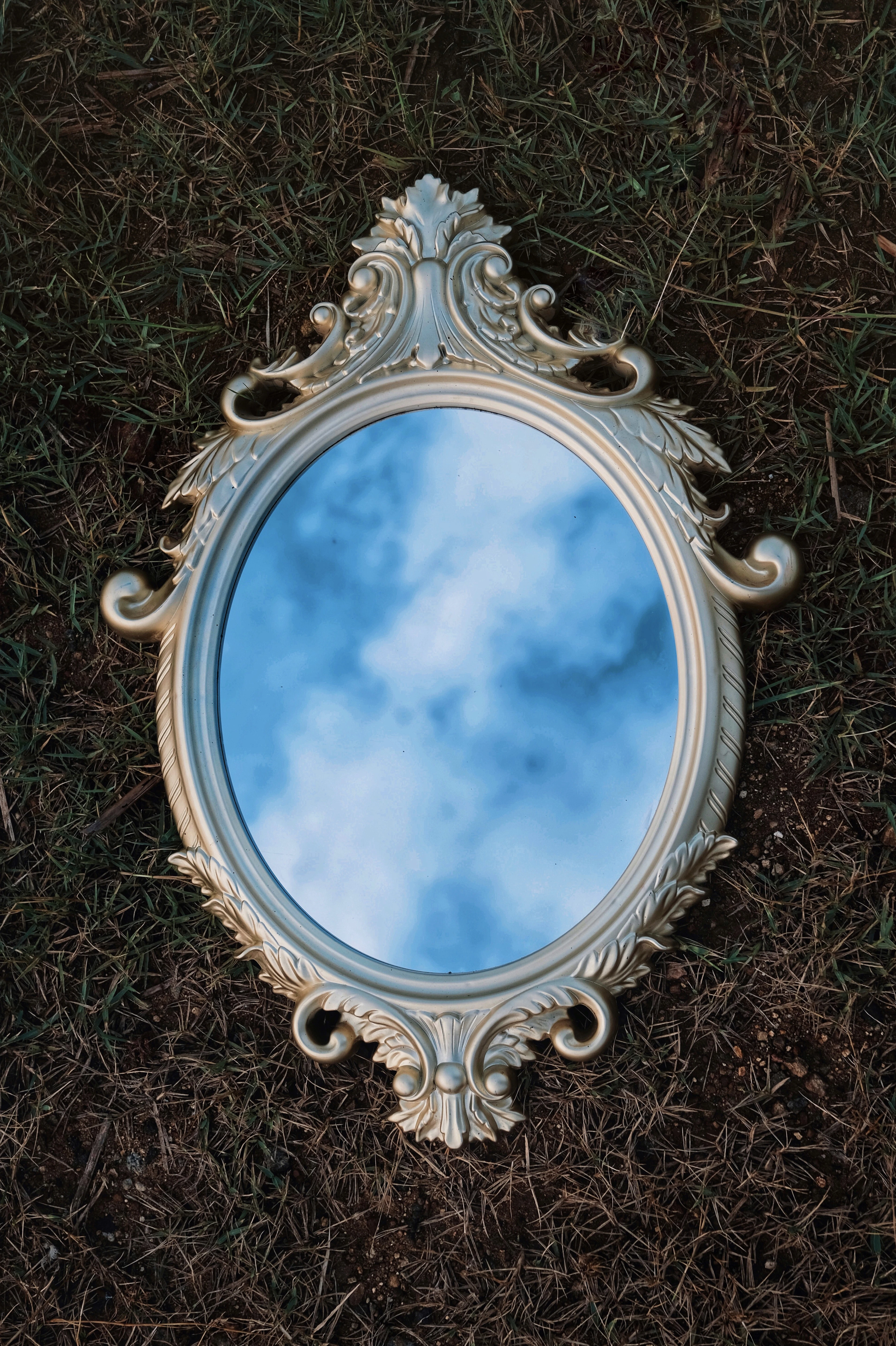Ornate gold oval mirror reflecting the sky