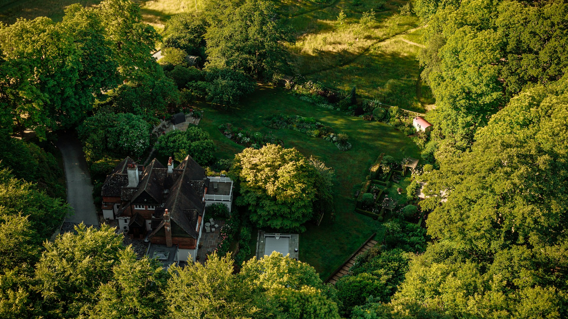 A stunning aerial drone shot capturing the sweeping view of a modern home surrounded by lush greenery at golden hour.