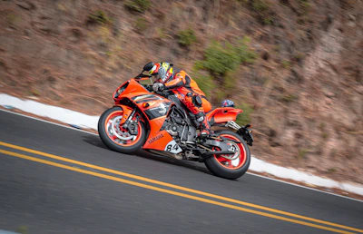 A vibrant red sportbike leaning into a sharp curve on a mountain road.