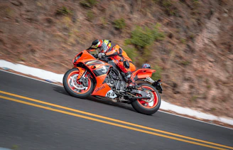 A vibrant red sportbike leaning into a sharp curve on a mountain road.