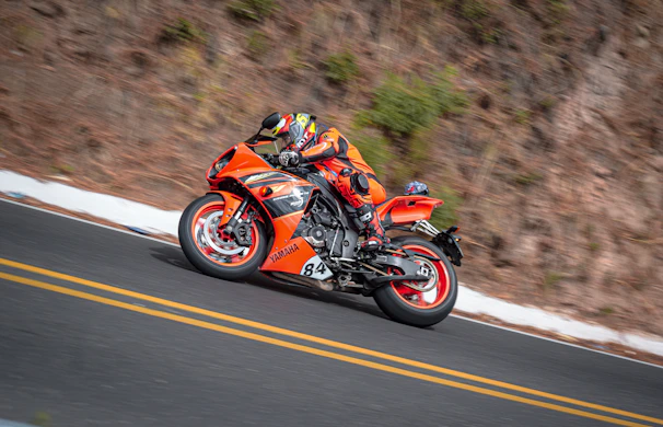 A vibrant red sportbike leaning into a sharp curve on a mountain road.