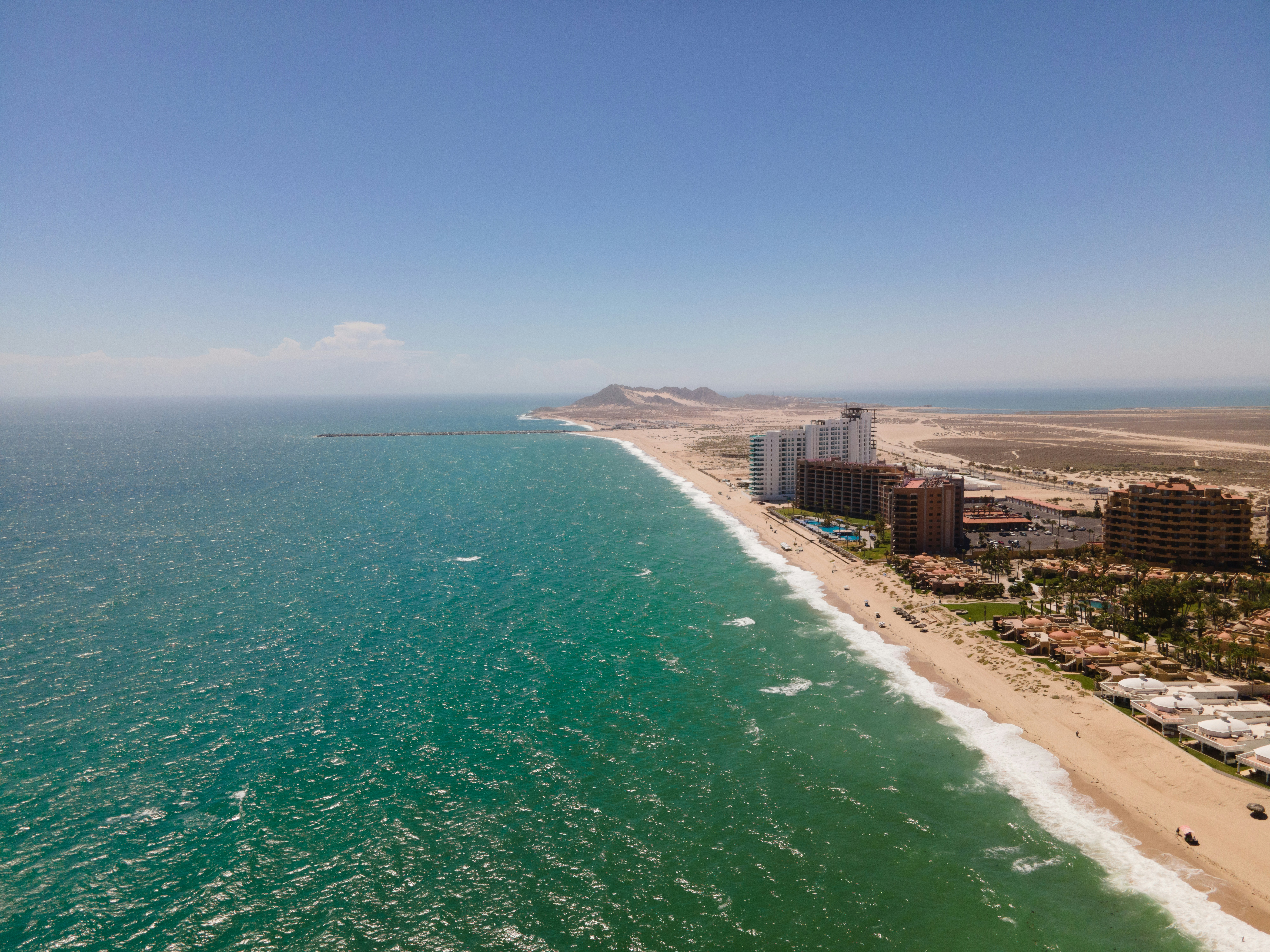 Aerial view of a luxury coastal destination with turquoise water and white sandy beaches under bright sunlight