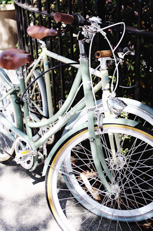 A vintage cruiser bike resting against a weathered fence with a steaming mug balanced on the seat.