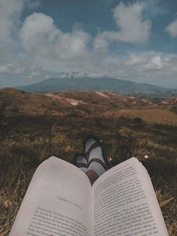 Close-up of an open book with Rousseau's writings beside a hiking boot on a trail.