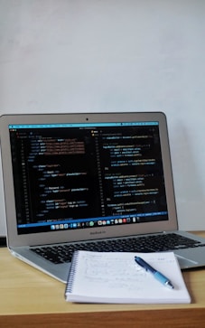 a laptop with a pen and paper on the table