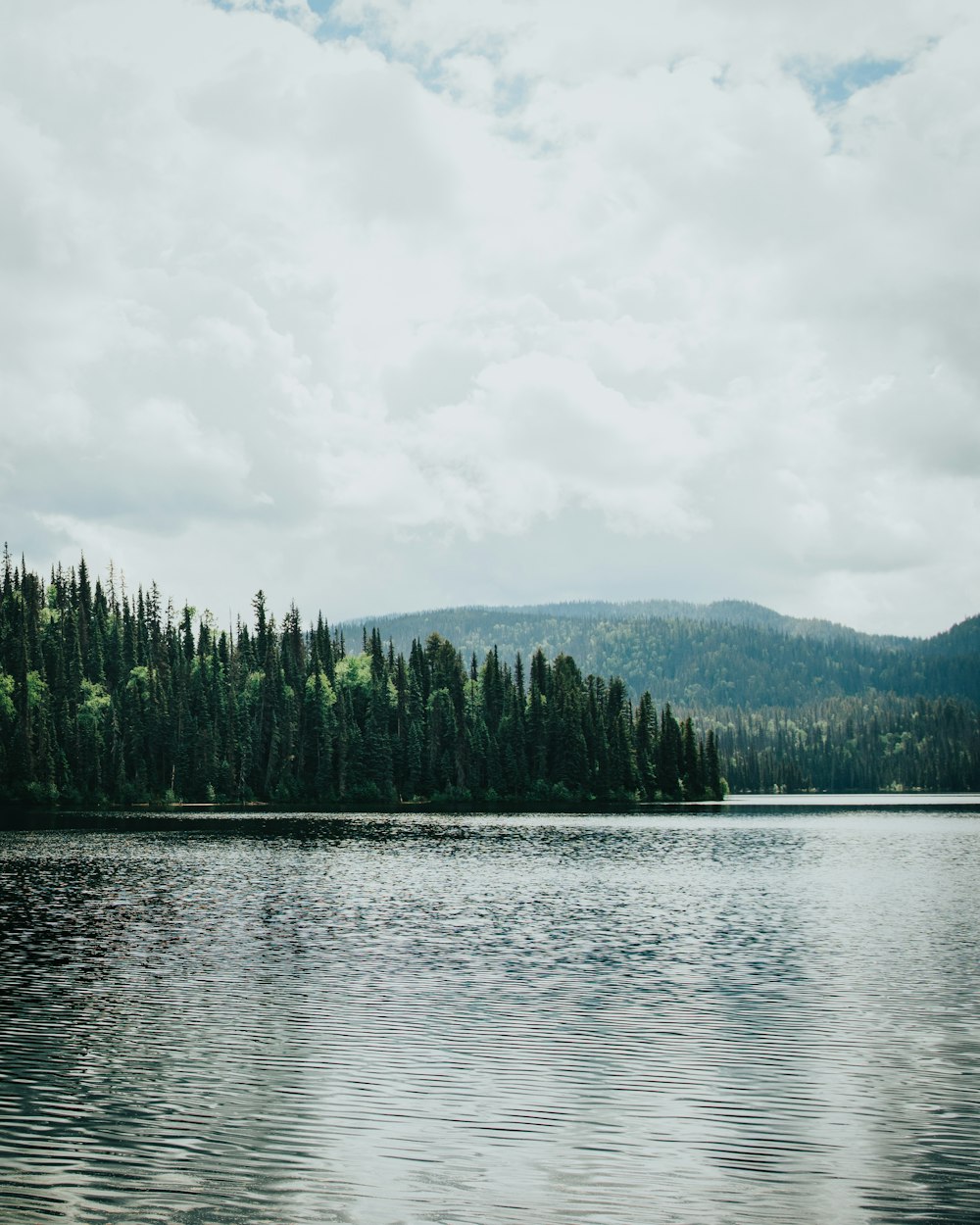 a lake with trees and mountains in the background