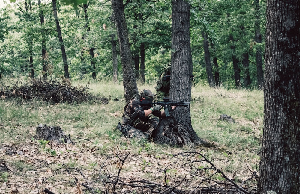 a person in camouflage holding a gun in a forest