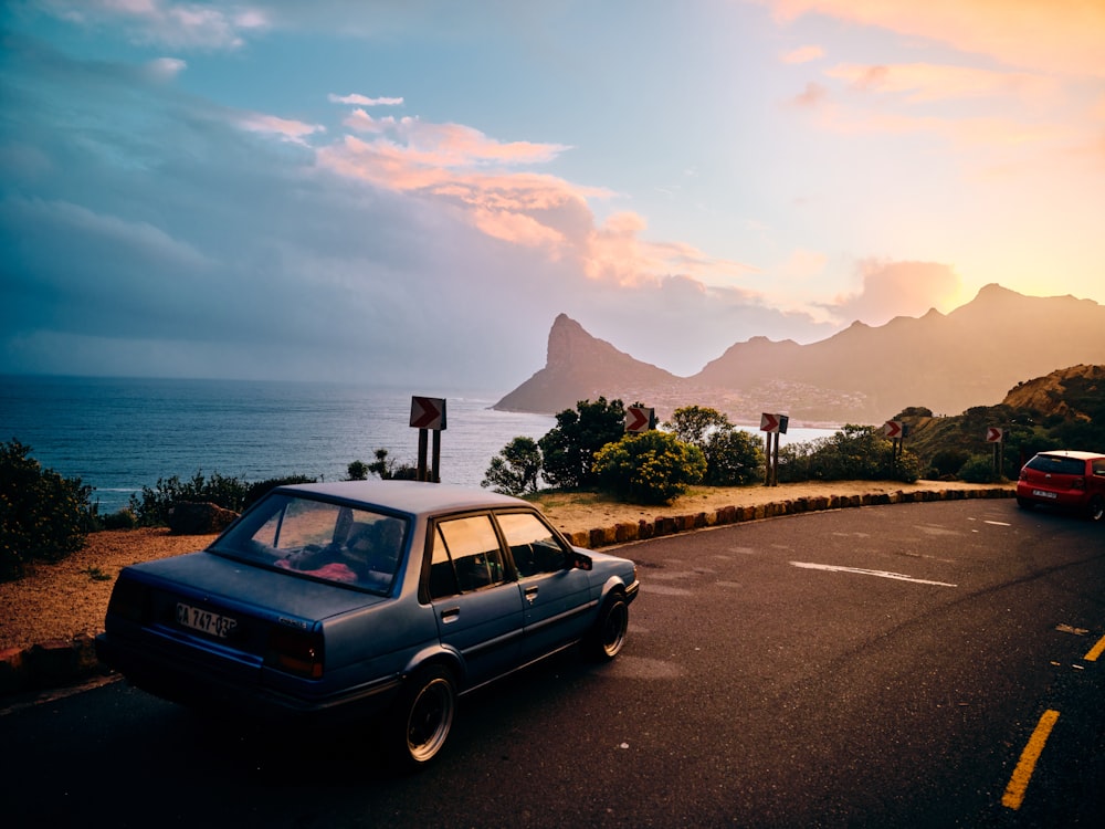 a car parked on the side of a road with a body of water in the background