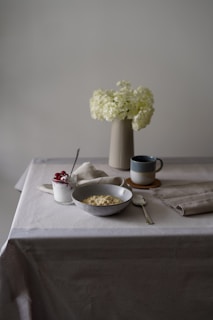 a table with a bowl of food and a vase with flowers
